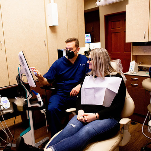 Dr. Jason explaining the dental procedure to her patient sitting in the dentist's chair