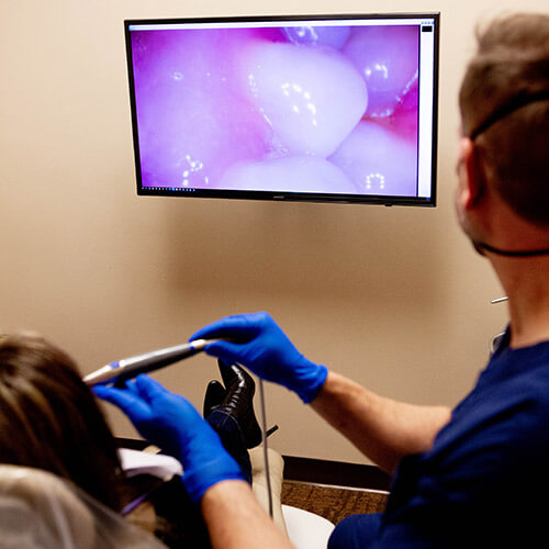 Dr. Jason using a video camera to check the teeth of her patient on a screen