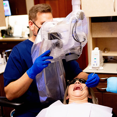 Dr. Jason using the microscope to check the teeth of his patient