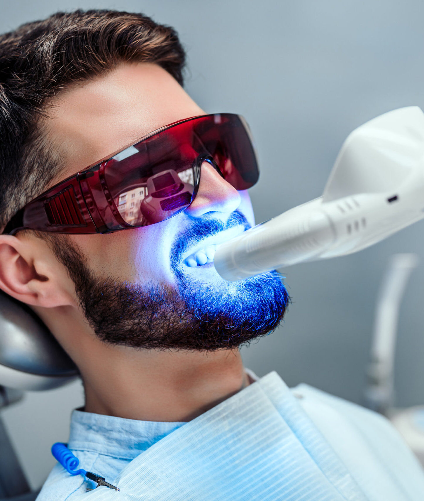 Close up view of man undergoing laser tooth whitening treatment to remove stains and discoloration.