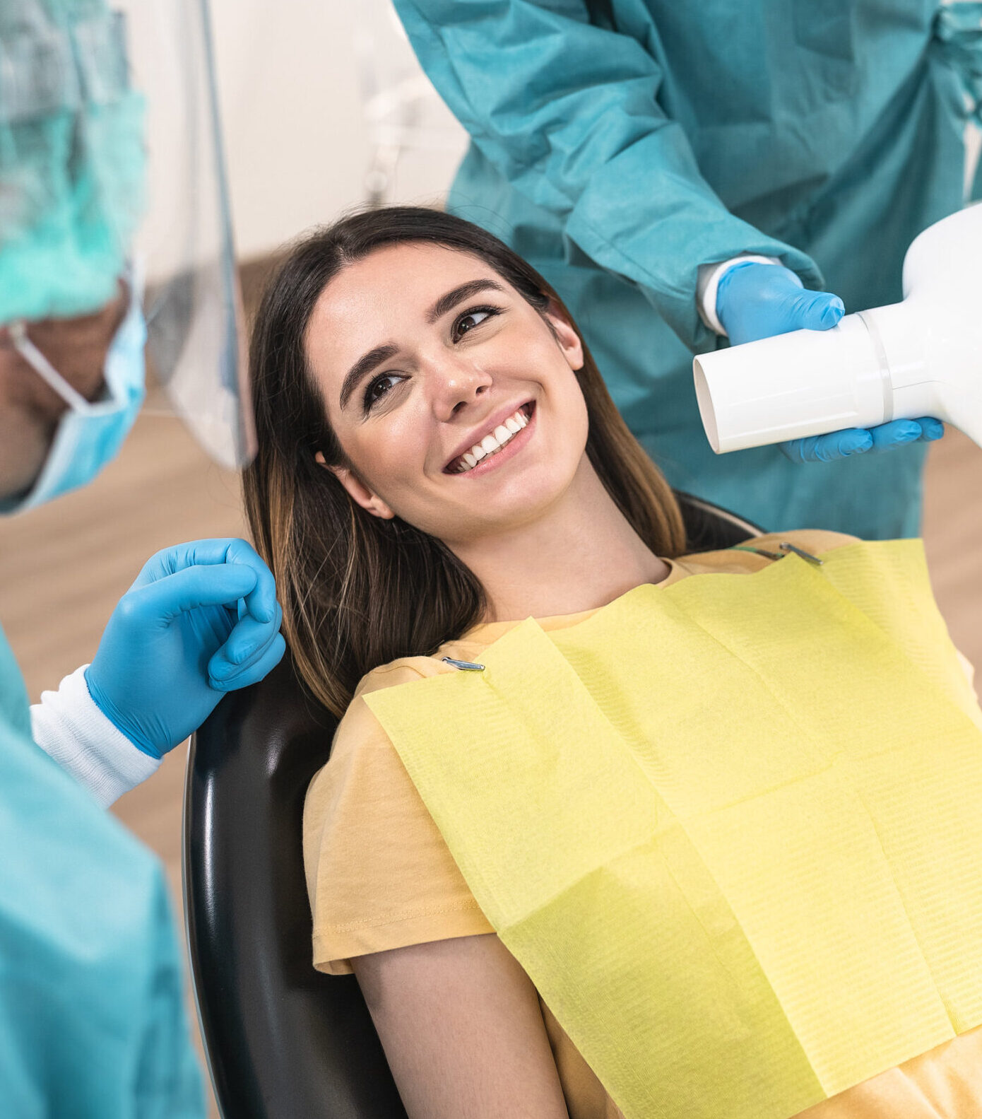 Man dentist operating young smiling woman in dental clinic - Oral heathcare assistance concept