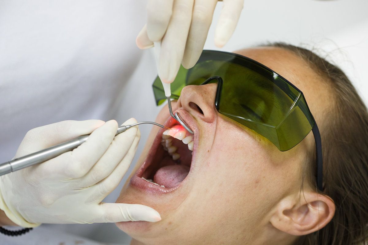 Dental procedure where professionals are attending to a patient using specialized tools and safety