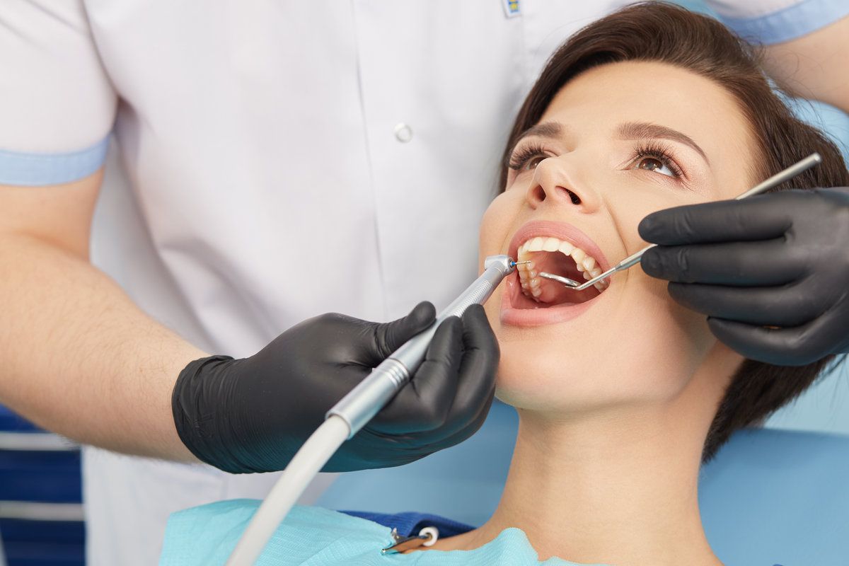 Young female patient visiting dentist office.Beautiful woman with healthy straight white teeth sitting at dental chair with open mouth during a dental procedure.Dental clinic.Stomatology.