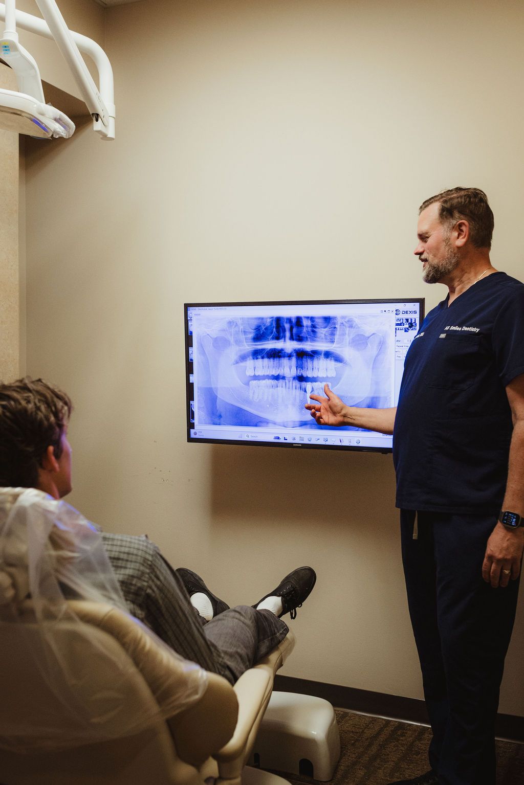 All Smiles Dentistry dentist reviewing panoramic X-ray with patient in consultation room