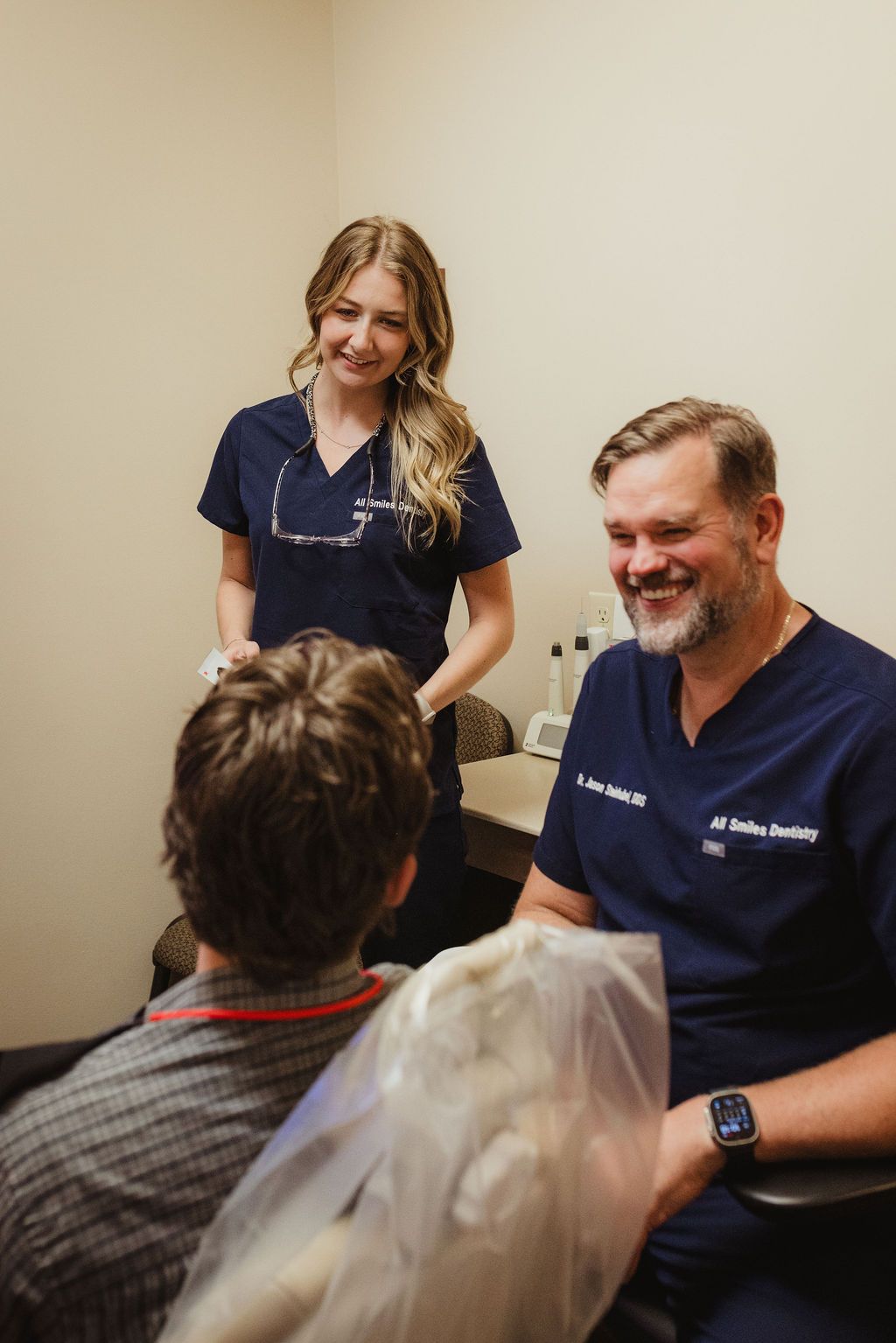 All Smiles Dentistry staff member and dentist consult with patient in treatment room