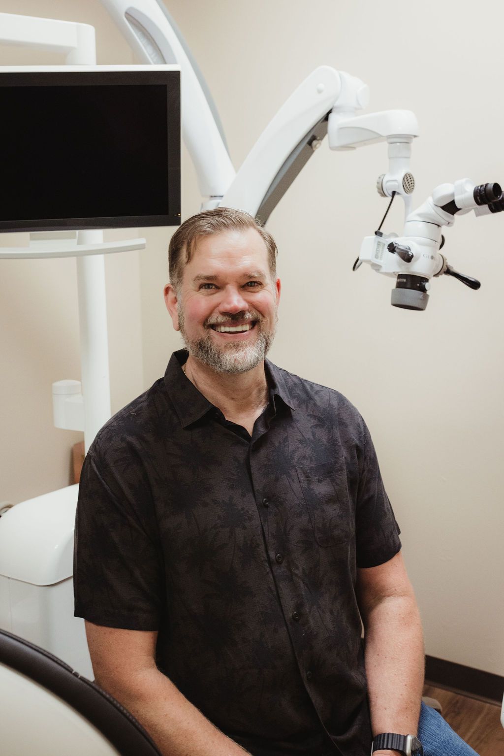 All Smiles Dentistry dentist portrait in clinical treatment room with surgical microscope