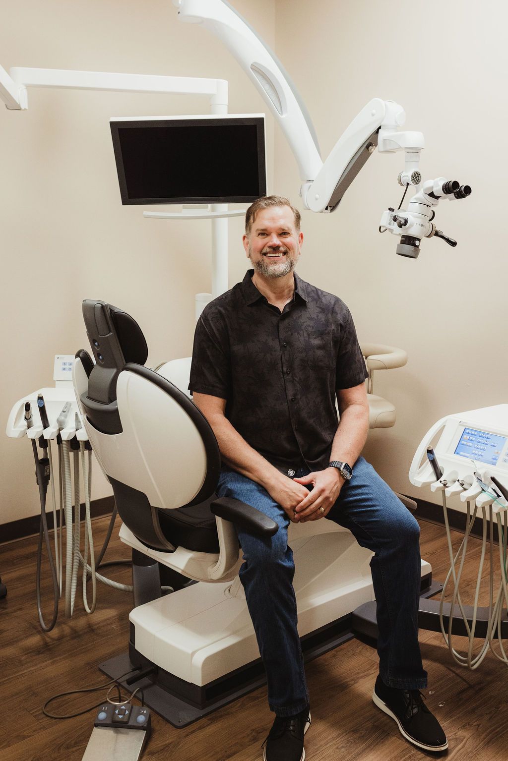 Dentist seated in operatory at All Smiles Dentistry with microscope