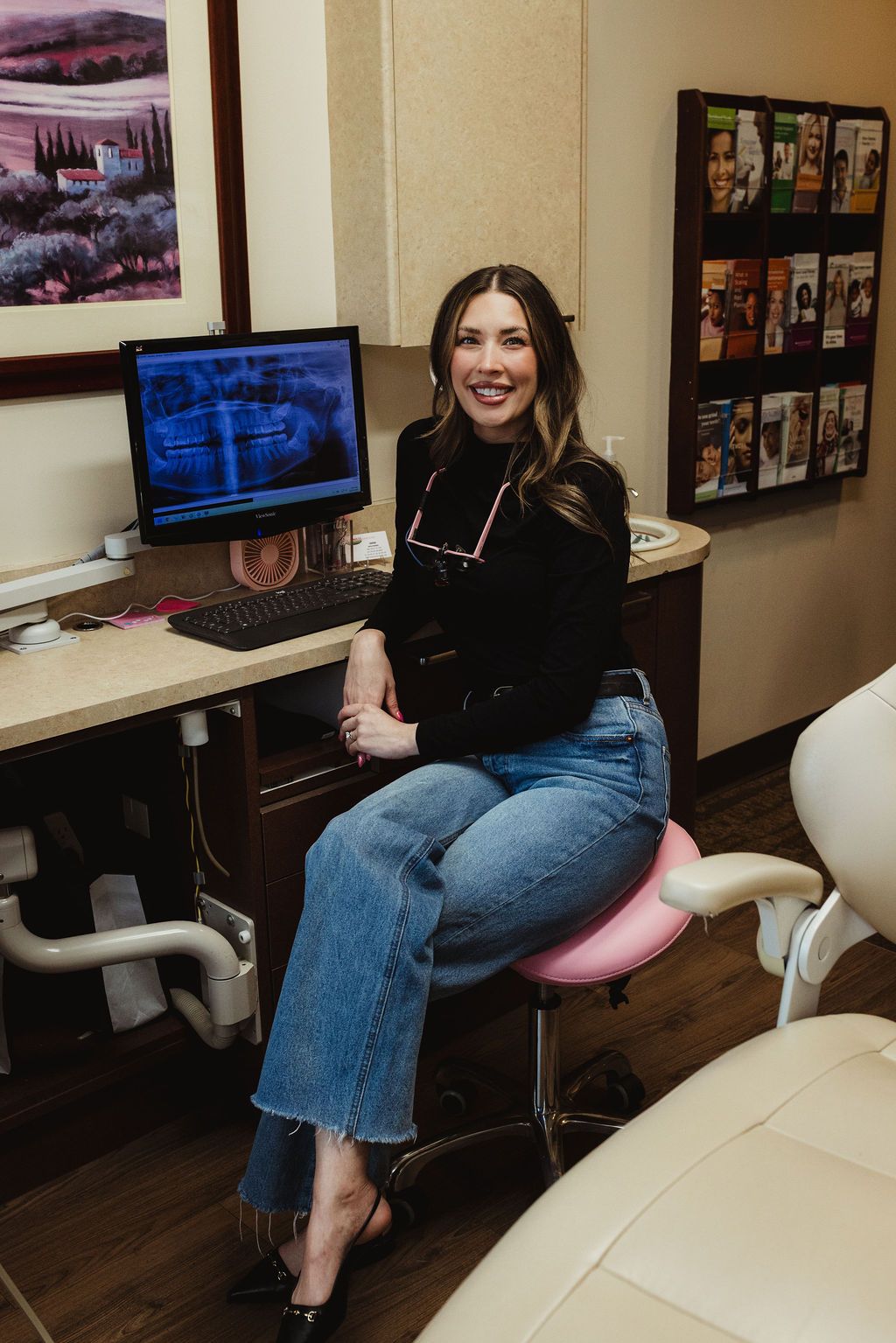 Dental professional at All Smiles Dentistry displaying panoramic X-ray on computer monitor