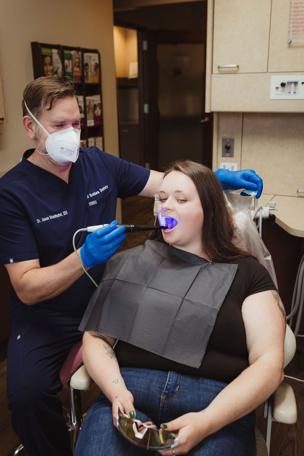 All Smiles Dentistry dentist performing whitening treatment on patient in exam room