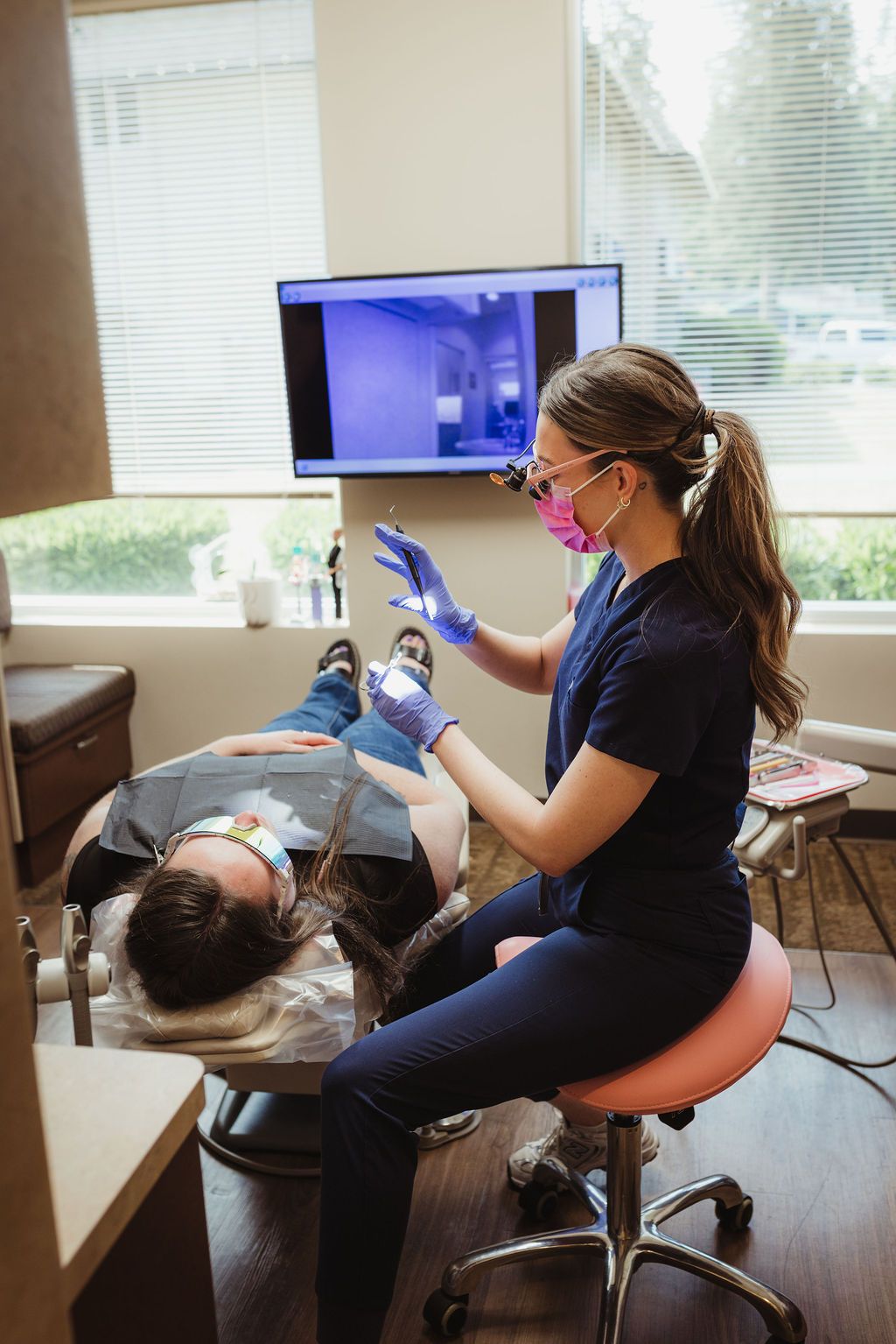 All Smiles Dentistry hygienist performing dental procedure on patient in clinical operatory