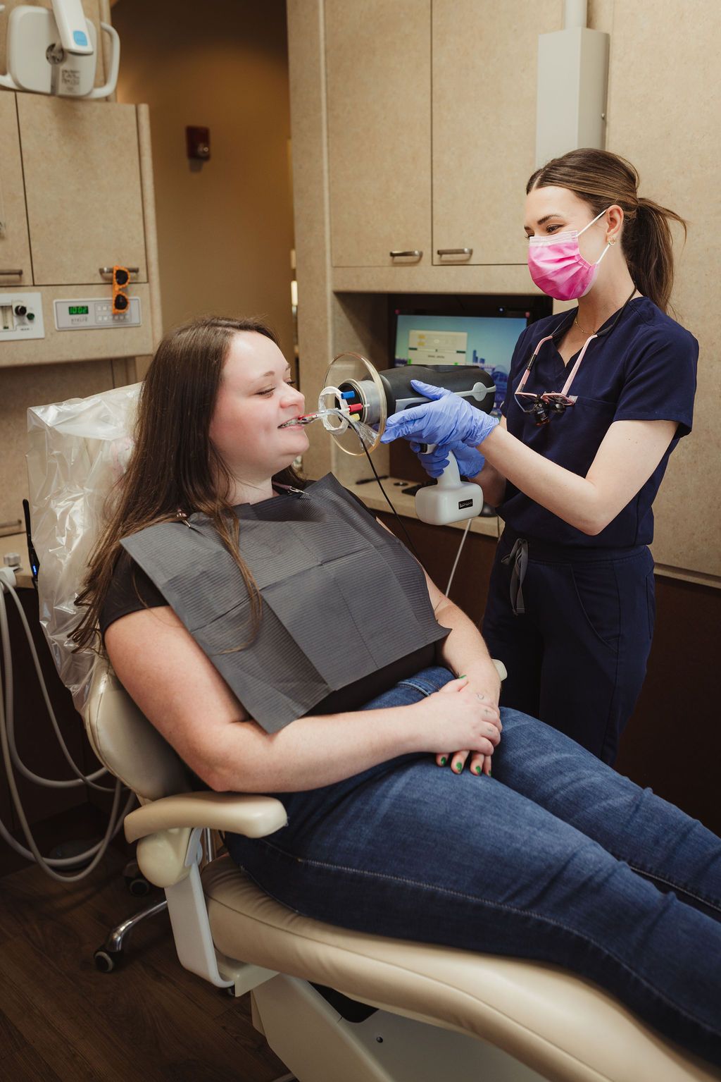 Dental hygienist performing intraoral scan on female patient in treatment room