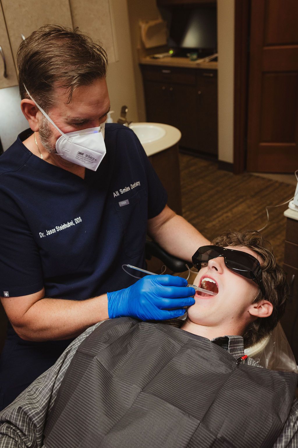 Dr. Jason Steintubel performs dental examination on patient wearing protective eyewear