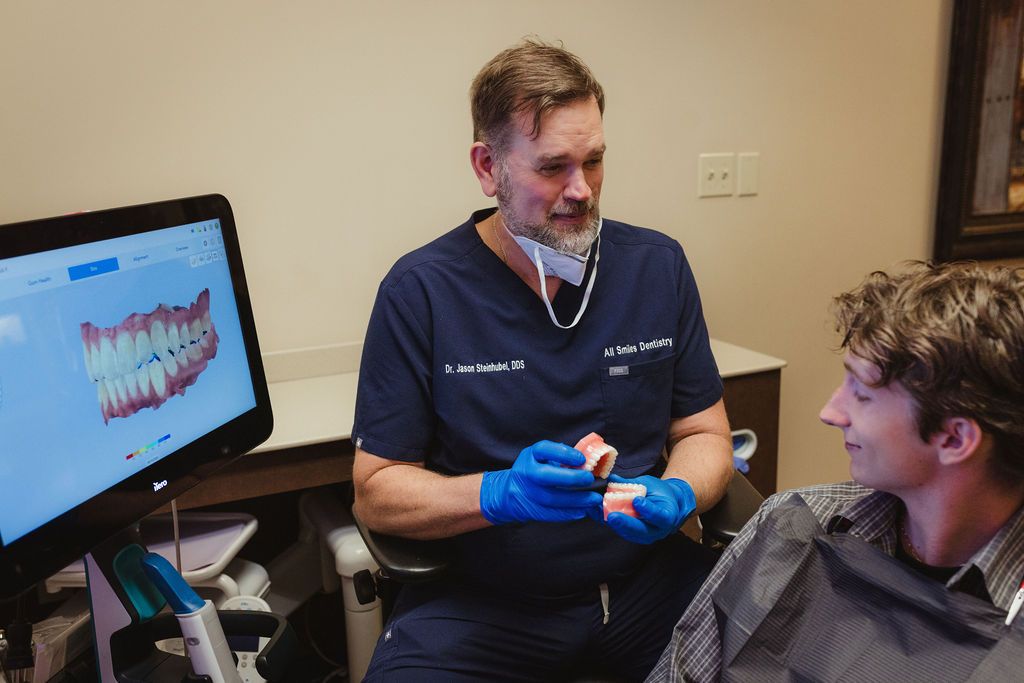 Dr. Jason Steintubel at All Smiles Dentistry explains dental model to patient with computer display
