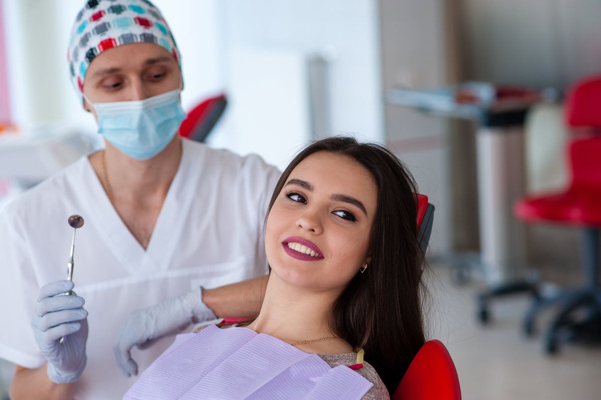 Dentist examining smiling patient in clinic
